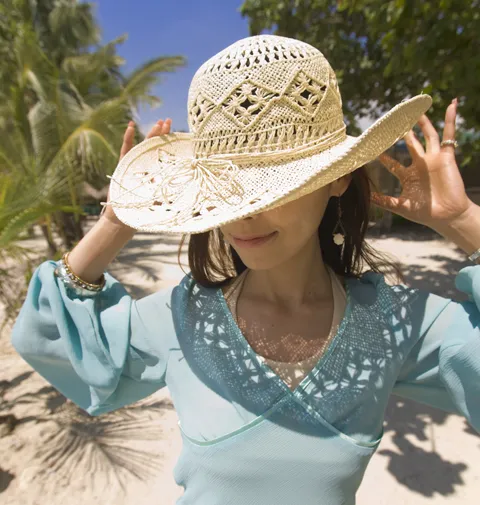 帽子で太陽からの日差しを防ぐ女性