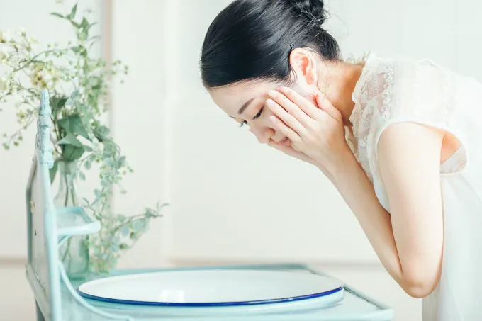水で顔を洗う女性